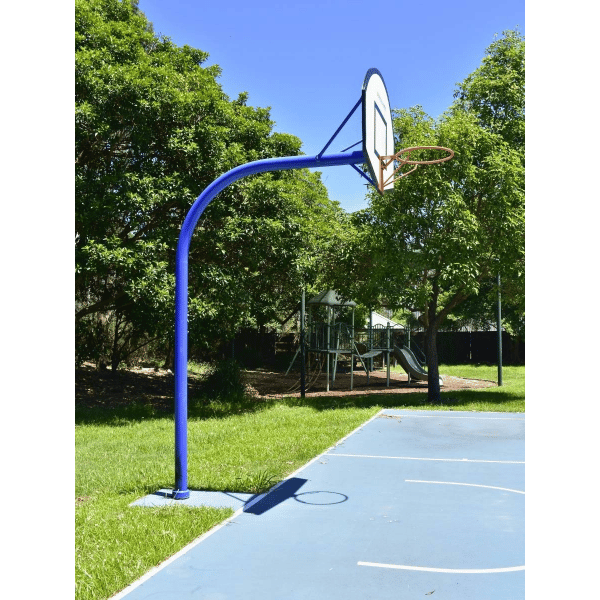 Grand Slam Arched Basketball Tower  on an outdoor court with trees and playground equipment in the background side facing