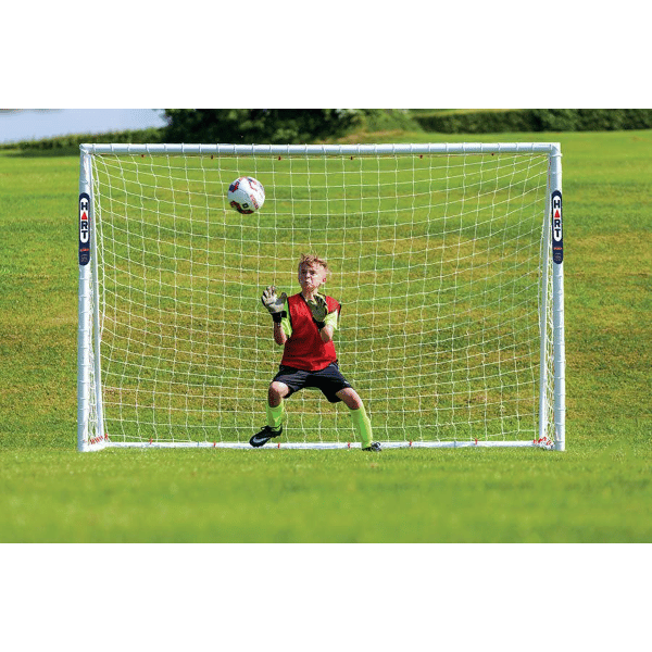 HART Samba Match Goals – goalkeeper in red and black uniform attempting save in front of white soccer goal on green grass field.
