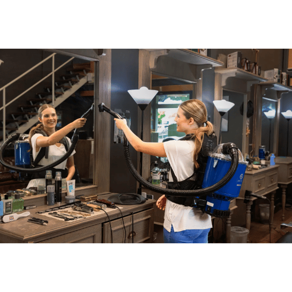 Person using the Pacvac Superpro Go Cordless Backpack Vacuum in a hair salon