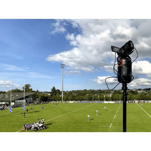 Rugby field with players and a Pix4team on a tripod against a blue sky.