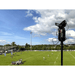 Rugby field with players and a Pix4team on a tripod against a blue sky.